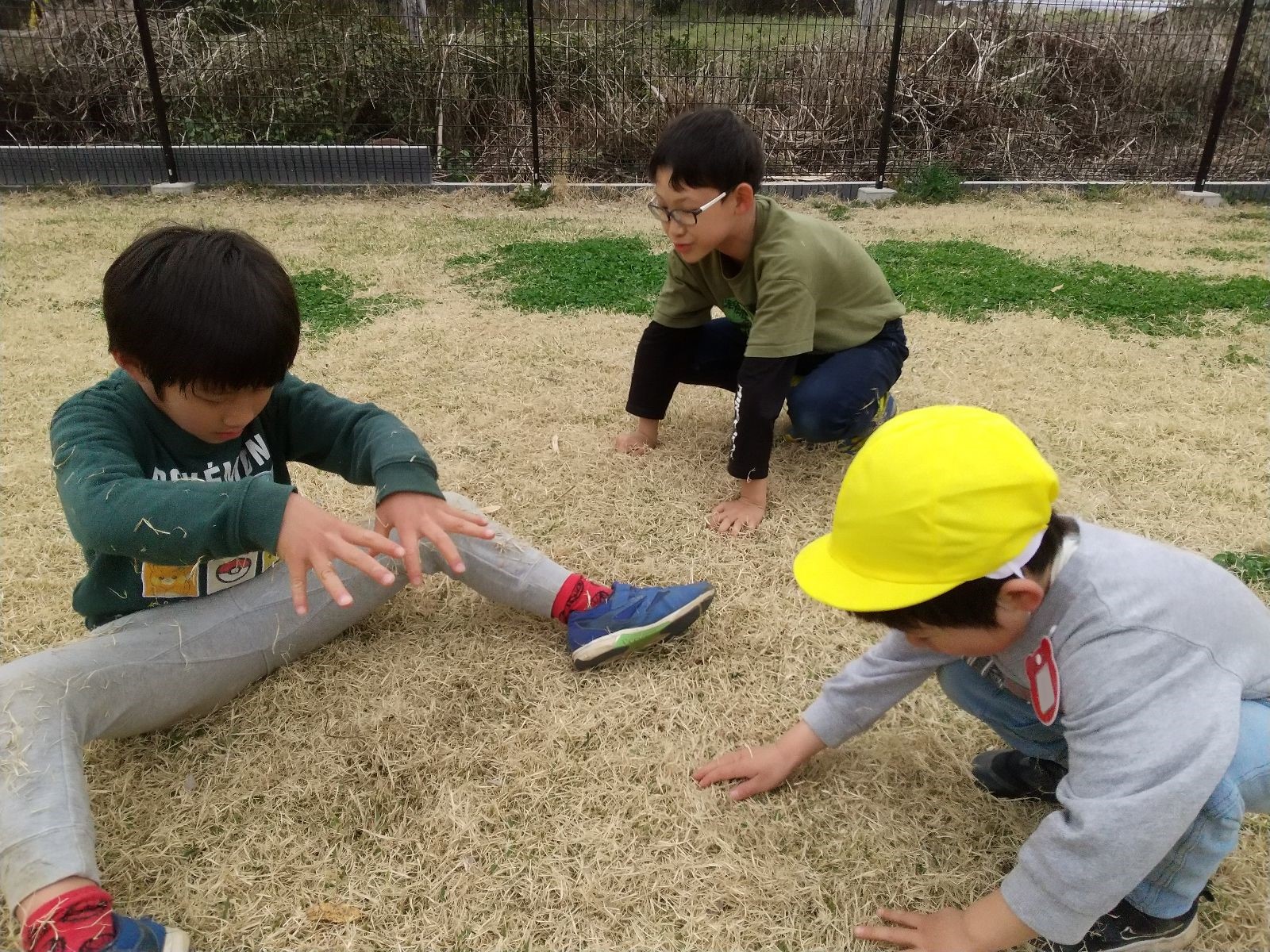 小学生と幼児が園庭で一緒に遊ぶ様子