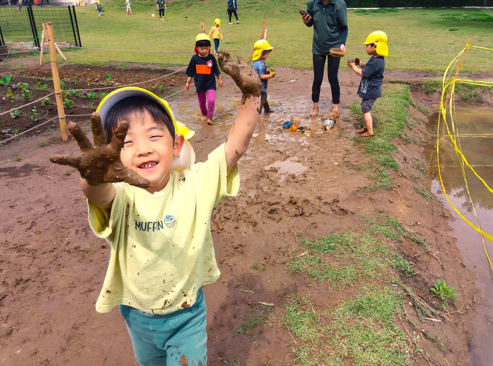 園庭の田んぼで泥遊びをする子どもたち