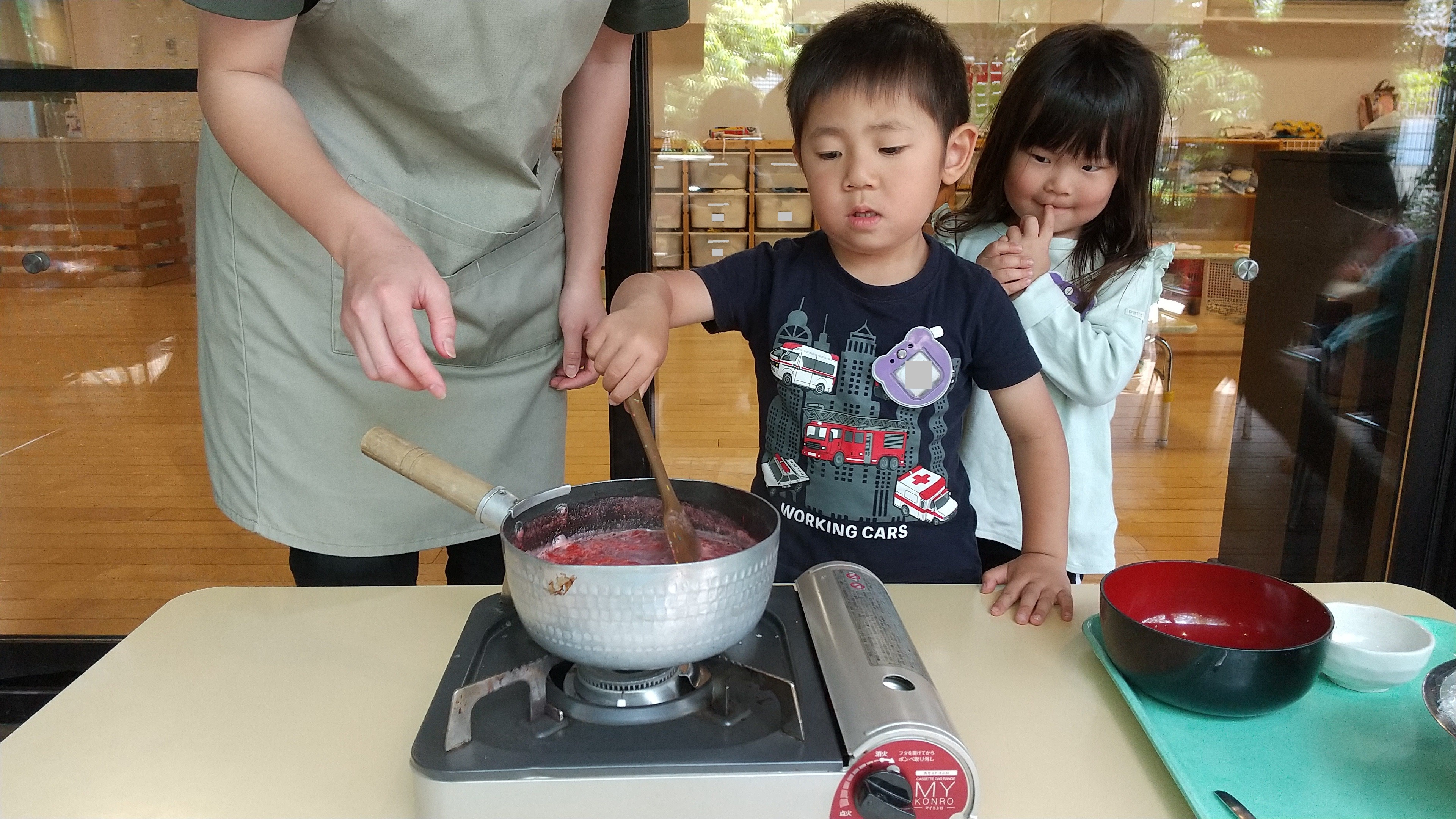 鍋に入れたイチゴを煮詰める子ども