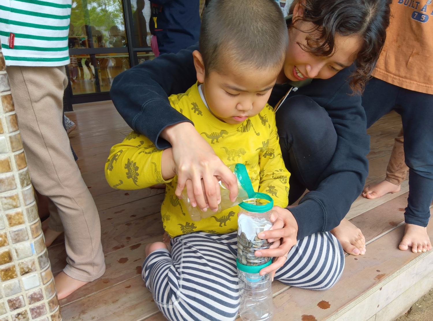 ペットボトルで作った簡易ろ過装置に水を入れる子ども