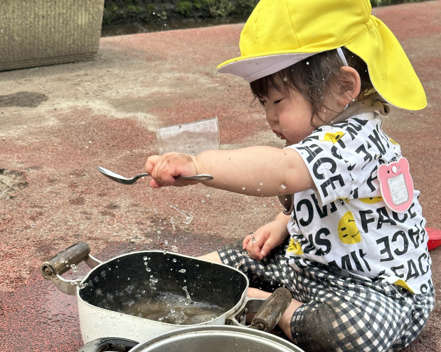 鍋に入れた水で遊ぶ子ども