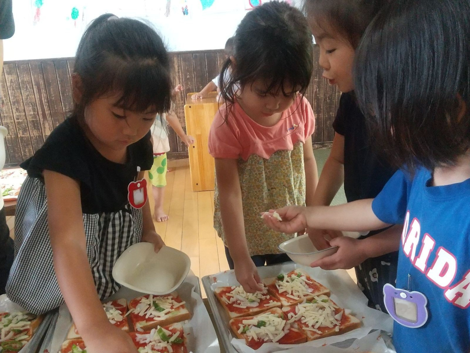 ピザ生地に具材を乗せていく子どもたち