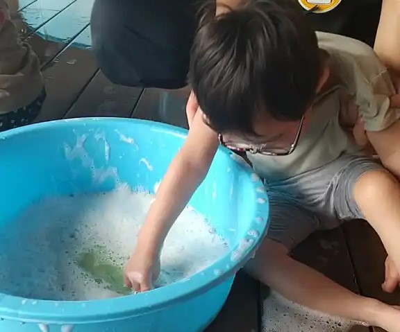 タライで水遊びをする子ども