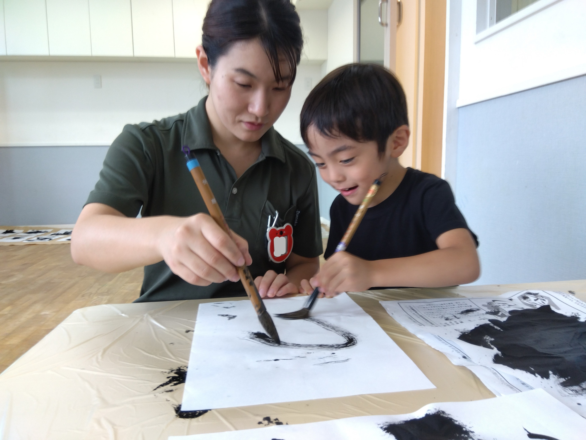 子どもと一緒に筆を走らせる施設長