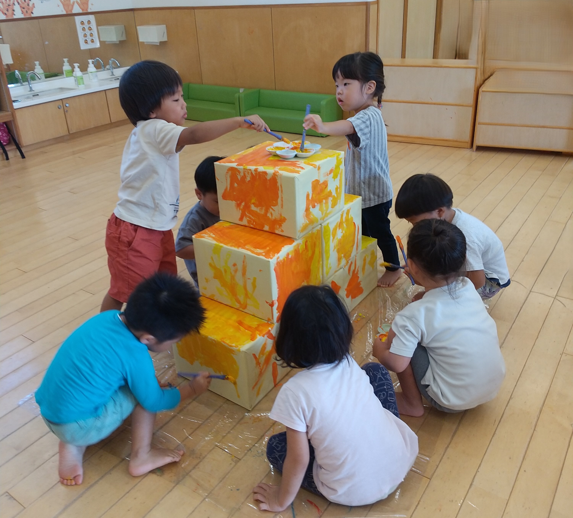 箱に絵の具で色を塗る子どもたち