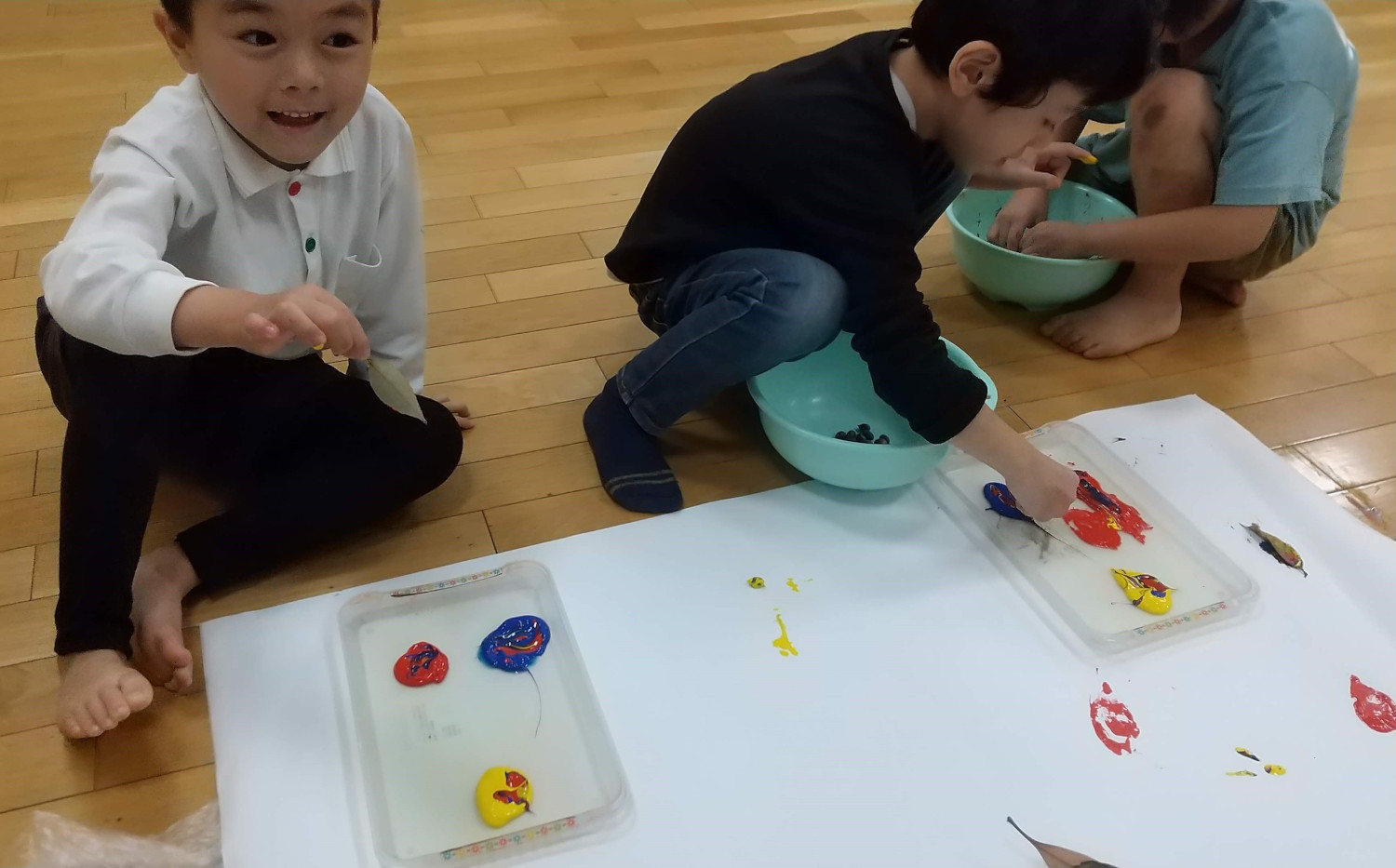 葉っぱに絵の具をつける子どもたち