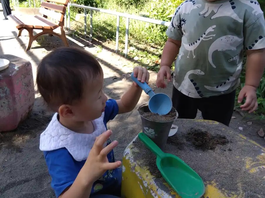 土をカップに入れる子ども