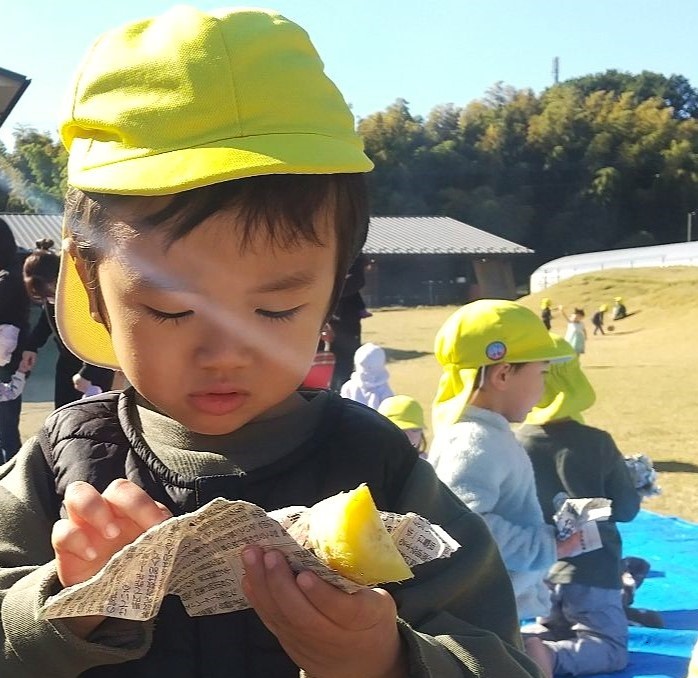 園庭で火を起こし焼き芋をたべる子どもの様子