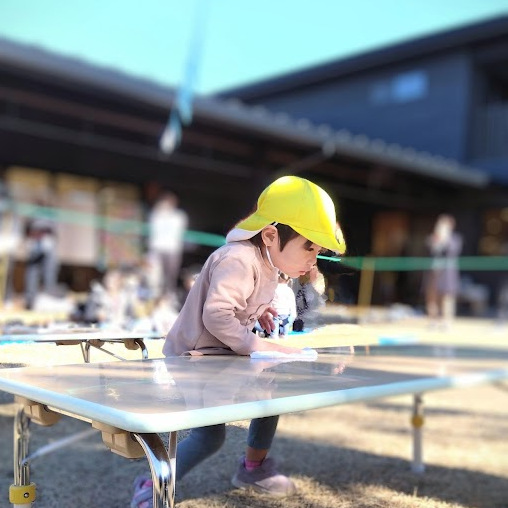 園庭にあるテーブルを拭く子ども