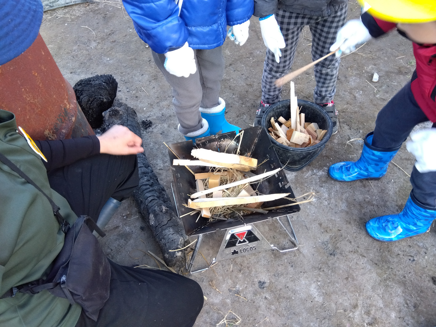 焚き火台に木を入れる子ども