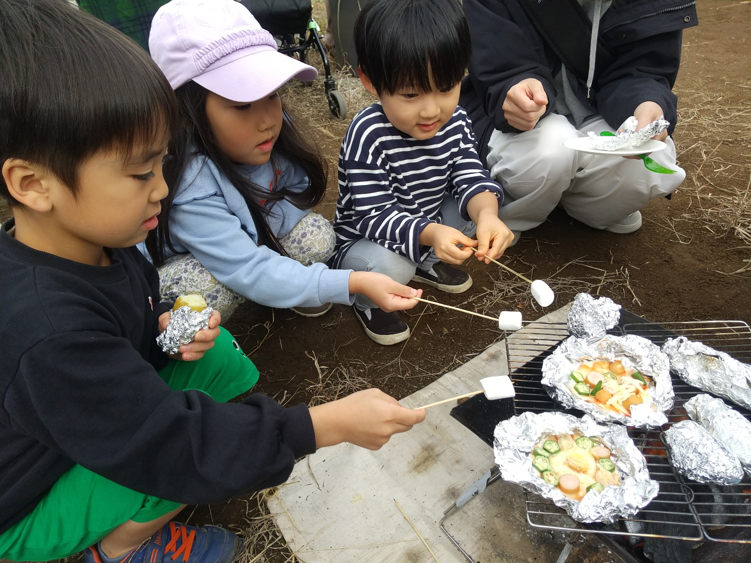 オクラを切ったり、餃子の皮にトマトソースを塗ったりする子どもたち