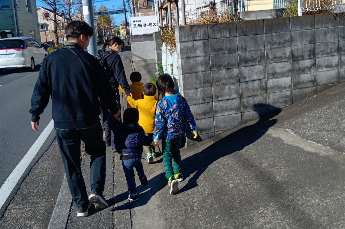 スタッフと手をつないで歩く子どもたち