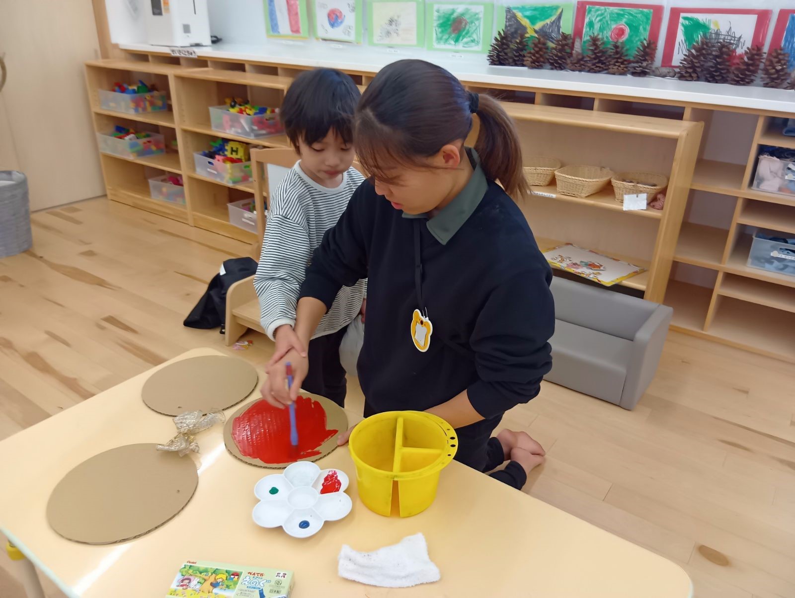 大人の手を借りながらクリスマスオーナメントを作る子ども