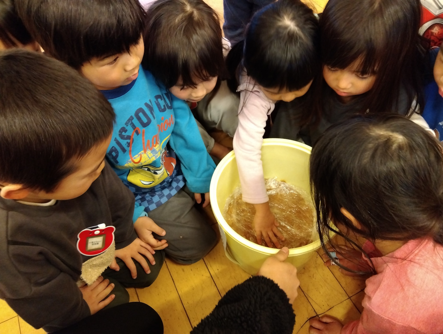 潰した大豆を容器につめる子どもたち