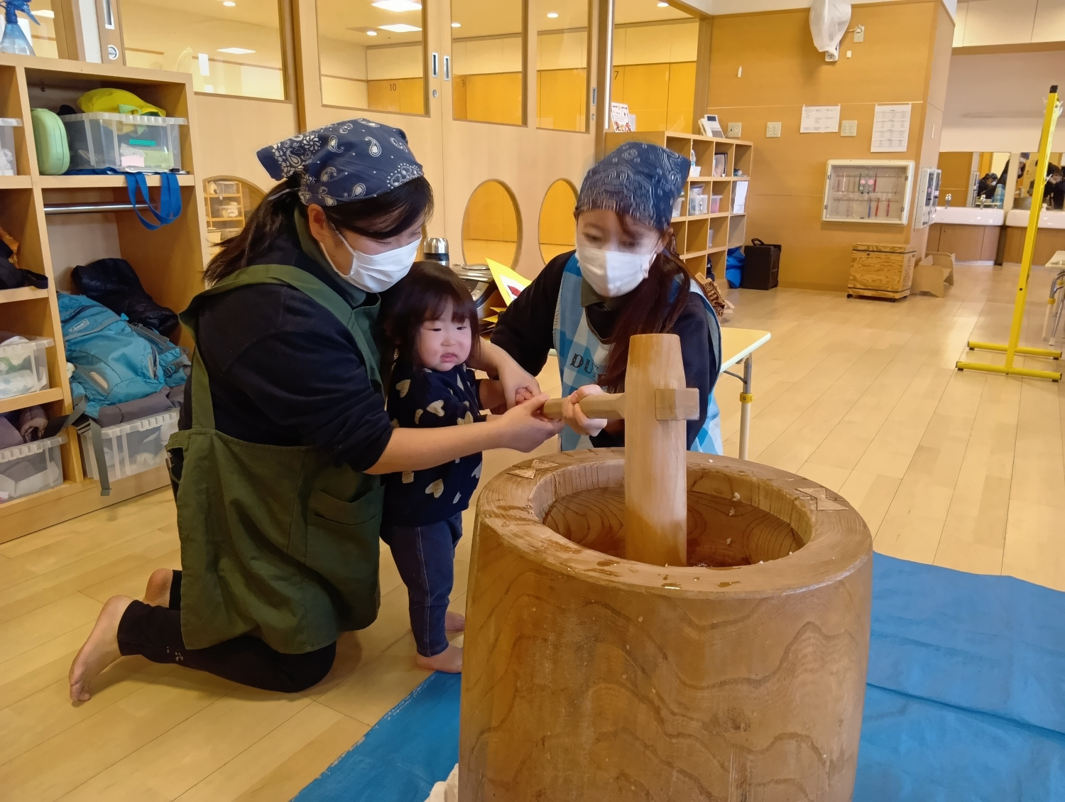 大人の手を借りながら餅をつく子ども