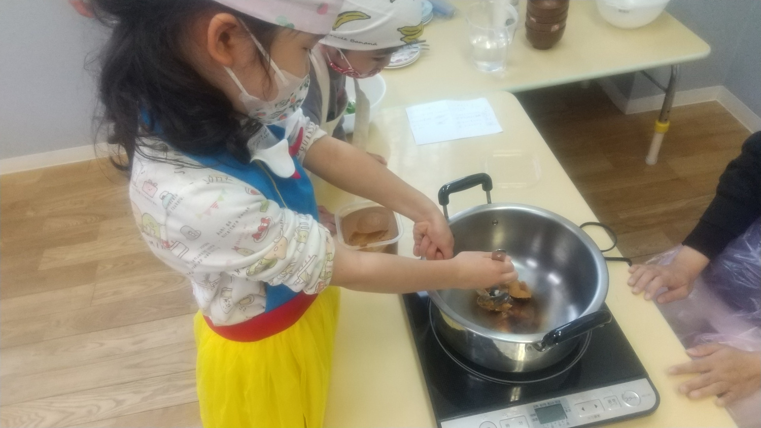 鍋で味噌を溶く子ども