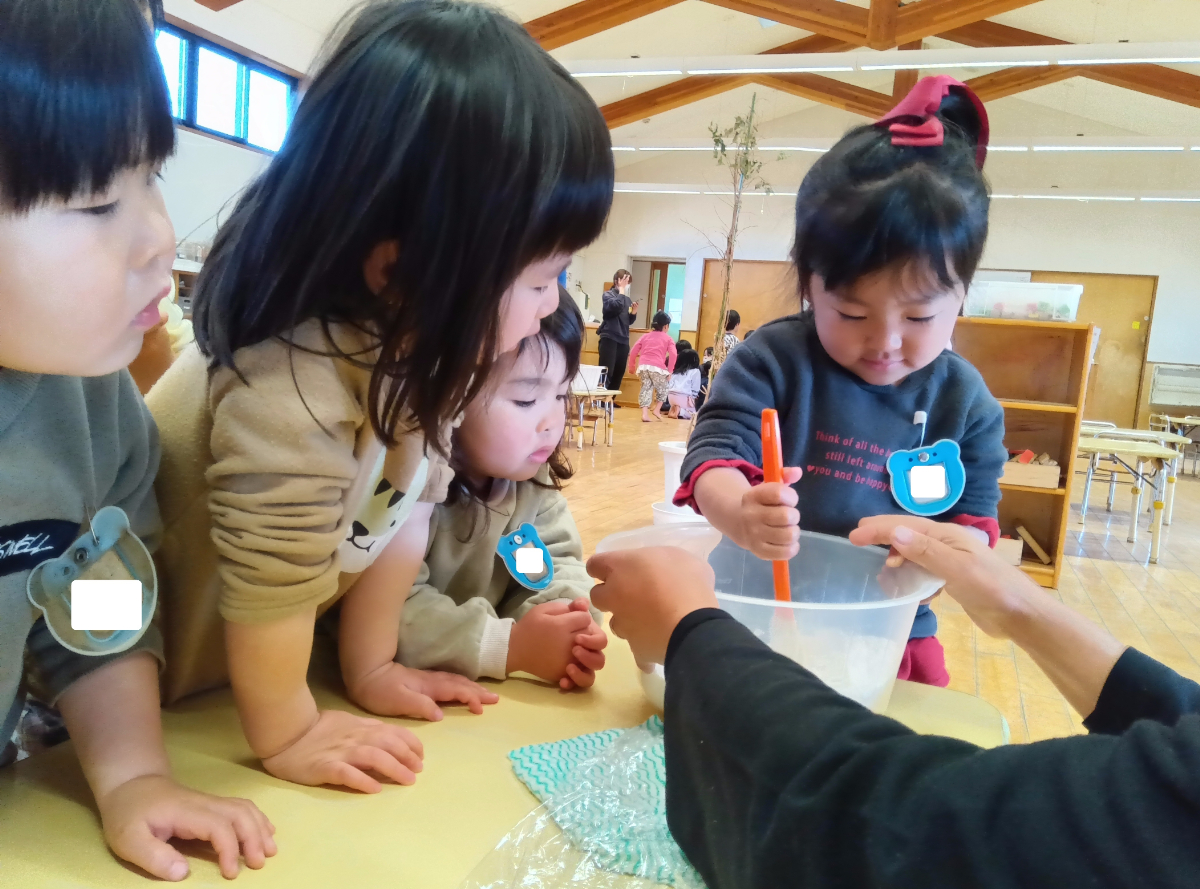 ボウルを混ぜる子どもを見守る子どもたち